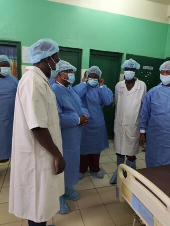 Des médecins et personnels soignants en tenue stérile échangent dans une salle opératoire de l’hôpital communautaire de Bangui.