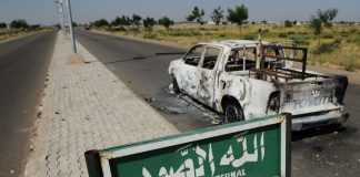 Une camionnette de patrouille de police brûlée reste abandonnée sur le bord d'une route déserte à Damaturu dans l'État de Yobe au Nigeria le 7 novembre