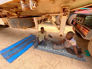 Deux assistants chauffeurs dorment sous leur camion immobilisé à Garoua-Boulaï, localité camerounaise frontalière avec la Centrafrique, le 24 janvier 2021