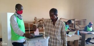 Un électeur jette le bulletin dans l'urne au centre de vote de l'école Koudoukou