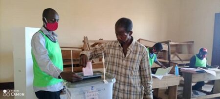 Un électeur jette le bulletin dans l'urne au centre de vote de l'école Koudoukou