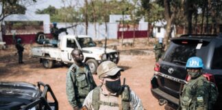 Un soldat de la Minusca, un paramilitaire russe et un membre de la garde présidentielle montent la garde pendant que Faustin-Archange Touadera vote à Bangui, en République centrafricaine, lors des élections présidentielle et législatives, le 27 décembre 2020. ALEXIS HUGUET / AFP