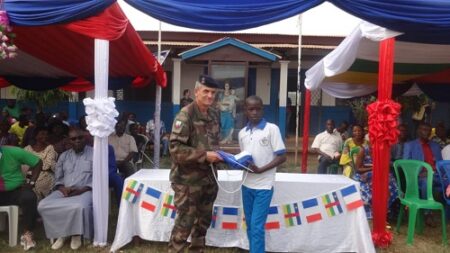 Le commandant Jean-Marie remet le kit à un élève du Lycée Don Bosco