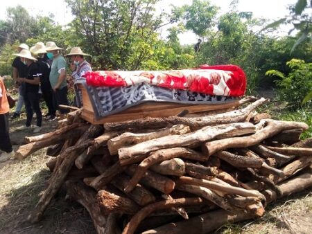 Le corps d'un des 9 chinois assassinés posé sur les morceaux de bois de son incinération