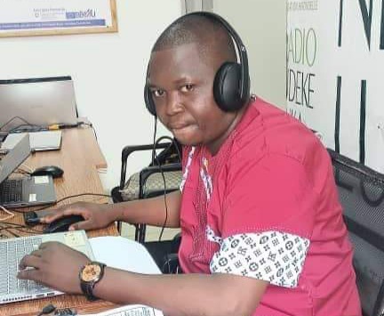 Le journaliste YALIKE NGONZO Ephrem Fidèle, habillé en chemise de couleur rouge, casque aux oreiles dans le studio de la radio Ndèkèluka