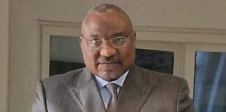 Monsieur Marcel Djimassé, ministre de la Fonction publique de Centrafrique habillé en costume devant son téléphone portable. Il porte ses verres progressives