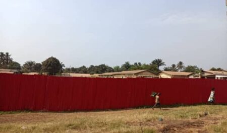 Le terrain du complexe sportif “24 Chambres” au Km5, vendu par Doneng et rapidement clôturer en tôle de couleur rouge pour les travaux de construction. 
