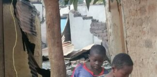 Deux adolescents curieux de même âge, un en chemise jaune et l’autre, dernier lui en chemise bleue tenant un ballon de foot à la main, entrain de marcher sur les gravats de la maison incendiée au quartiers Castors à Bangui