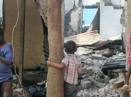 Deux adolescents curieux sur le site de la maison incendiée au quartier Castors à Bangui. Le plus grand en chemise bleu et le plus petit en chemise multicolore, collant à l’arbre en train d’observer les dégâts. 