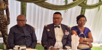 Le chef d'état-major, le général Zéphirin Mamadou habillé en tenue confectionnée pour la fête, cravatte papillon, chemise blanche devant une assiette, couvert et un verre d'eau servi sur la table, sa femme à sa gauche. Et au milieu est à sa droite le ministre de la Défense Biro.