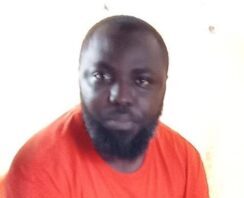 Homme nommé Totte Nzapali Lewis Eman en t-shirt orange. Totte-Nzapali-Lewis-Eman La Supercherie d‘un officier Fantôme  chez le ministre Maxime Balalou : Révélations d’un Faux Recruteur dans les rangs des FACA