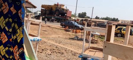 Un camion militaire transportant un équipement d’exploitation minière traverse la ville de Bangui, ici, à Gobongo, sur l’avenue du 15 mars à Bangui, bordée de commerces et de taxis.