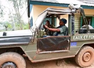 Deux agents des eaux et forêts discutant dans un véhicule tout-terrain boueux marqué de l’insigne de l’Union Européenne dans une zone forestière.