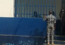 Un agent de sécurité observe les détenus derrière les barreaux de la prison de l’OCRB au centre-ville de Bangui.
