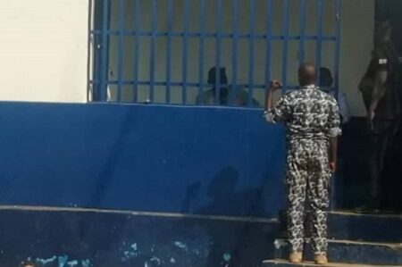 Un agent de sécurité observe les détenus derrière les barreaux de la prison de l’OCRB au centre-ville de Bangui.