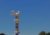 Un monument avec une sculpture de colombe blanche surmontant un pilier orné de bandes colorées, situé dans la ville de Paoua.