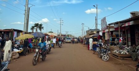 Rue animée avec des marchands ambulants et des motos dans le quartier PK5 de Bangui, montrant l’activité commerciale locale