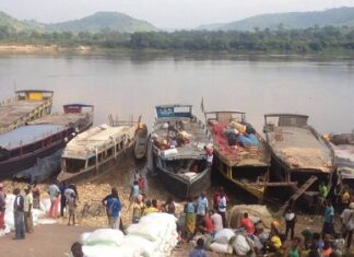 Baleinières stationnées sur la rivière Oubangui avec des gens et des sacs de marchandises.