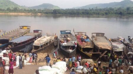 Baleinières stationnées sur la rivière Oubangui avec des gens et des sacs de marchandises.