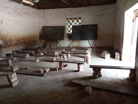 Photo montrant l’intérieur d’une salle de classe délabrée à Yalinga avec des bancs en bois et un tableau noir.