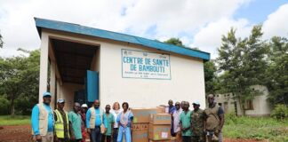 Équipe de l’UNICEF et personnel local devant le Centre de Santé de Bambouti avec des cartons de médicaments.