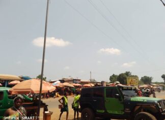 Vue d’une rue animée à l’entrée du marché Gobongo, à la sortie nord de Bangui, avec des véhicules, des piétons et des vendeurs ambulants.
