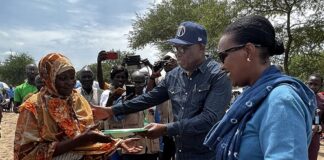 Un représentant des autorités locales remet des documents à une réfugiée soudanaise lors du transfert vers un camp permanent en République centrafricaine.