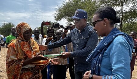 Un représentant des autorités locales remet des documents à une réfugiée soudanaise lors du transfert vers un camp permanent en République centrafricaine.