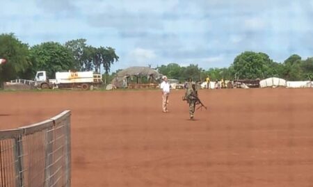 Un civil et un mercenaire russe armé patrouillant sur la piste de l'aérodrome de Birao