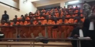Prisonniers en tenue orange assis dans une salle d’audience lors de la première session criminelle ajournée à cause de fuites d’eau dues à la pluie.