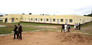 Image du centre hospitalier de Délébama montrant des bâtiments modernes mais désertés, avec des personnes se promenant autour.