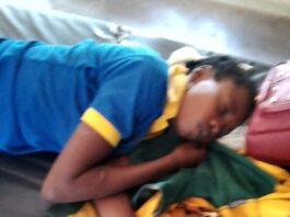 Jeune fille en uniforme scolaire bleu et jaune dormant sur un sac à dos jaune