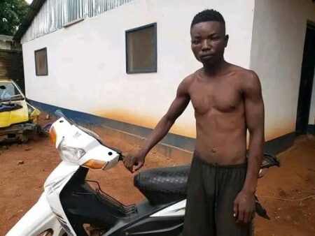 Homme torse nu debout à côté d’une moto