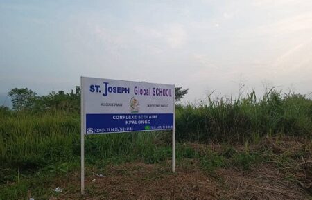 Panneau indiquant l'emplacement futur de l'école St. Joseph Global School au village Kpalongo, sur la route de Mbaïki