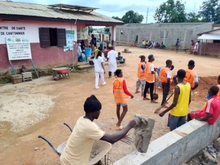 Les jeunes de la localité, équipés de gilets de sécurité, nettoient et rénovent les abords du centre de santé de Cantonnier sous la supervision des soldats de la MINUSCA