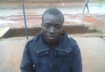 Le policier Symprorien Kenféi en uniforme bleu foncé regardant la caméra