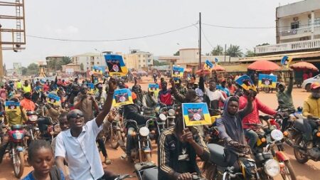 Foule de manifestants à moto brandissant des drapeaux russes dans une rue de Bangui