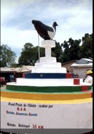 Rond-point de l'Unité à Bétoko avec une statue d'oiseau au sommet, peint aux couleurs du drapeau centrafricain