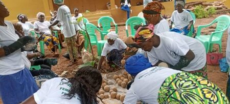 Un groupe de femmes du cinquième groupement de Mbaïki, de l'association Sara Savon de Mbaïki, assises autour d'une table et impliquées dans une activité collective. Corbeaunews-Centrafrique