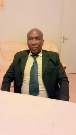 Fidèle Hintia, président de la Commission Nationale d'Évaluation du CNCA-PDD, en costume vert et cravate, dénonçant le calvaire social des Centrafricains sous le régime Touadera