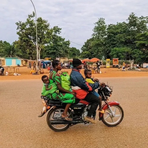 Un moto-taximan porte une femme et ses deux enfants sur l'avenue des Martyres devant l'Université de Bangui. Photo CNC