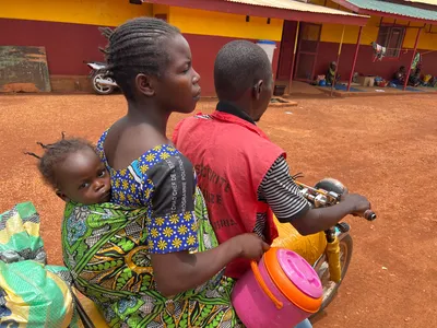 Une mère portant son bébé dans le dos, en pagne , voyage à moto financé par le MSF à Bria pour rejoindre l'hôpital de Bria. Photo MSF